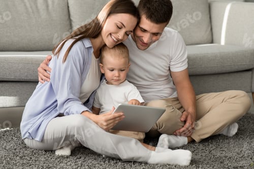 Preview: Cute Infant Boy Using Digital Tablet While Relaxing With Parents At Home