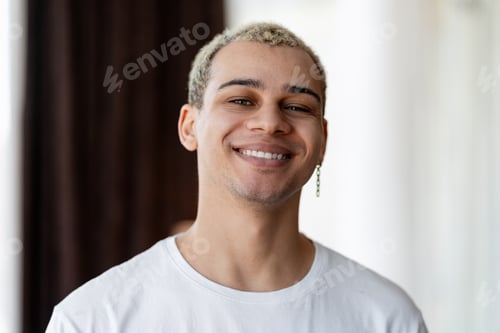 Preview: Smiling young man expressing happiness and joy, wearing a white t shirt and earring
