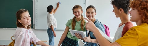 Preview: Schoolboys talking and pointing near friends and blurred african american teacher in class, banner