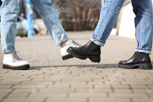 Preview: People greeting each other by bumping feet instead of handshake outdoors, closeup