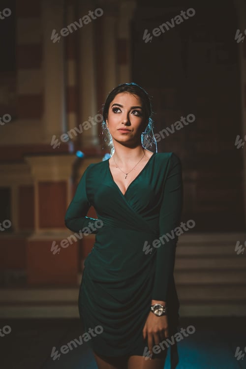 Preview: Vertical shot of a young Caucasian female posing in an elegant green dress at night