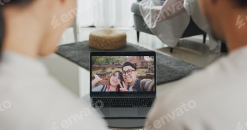 Preview: Couple looking at laptop screen talk video call with friends at home on holiday.