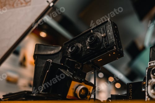 Preview: old camera to take photos with two small lenses on a small stand next to other old cameras exposed