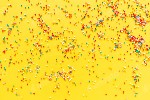 Preview: Multicolored candy dragees on yellow background. Top view. Flat lay. Festive, birthday celebration
