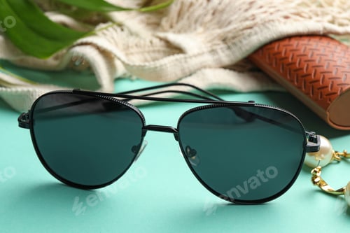 Preview: Stylish elegant sunglasses on turquoise background, closeup
