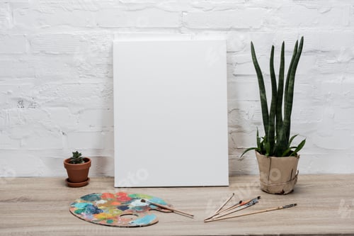 Preview: close up view of empty drawing easel and plants in flowerpots on table