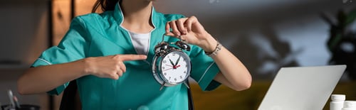 Preview: panoramic shot of nurse in uniform pointing with finger at alarm watch during night shift