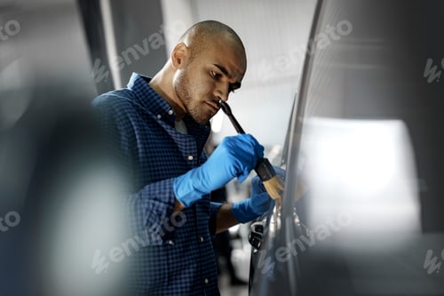 Preview: African American man car service worker applying nano coating on a car