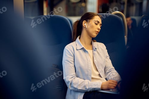 Preview: Young woman taking a nap while commuting by train.