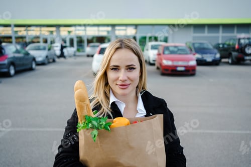 Preview: An outdoor portrait of a smiling woman, surrounded by lush greenery, holding a paper bag filled with