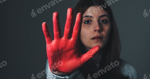 Preview: Sad girl raises her hand painted red to stop and protest against violence