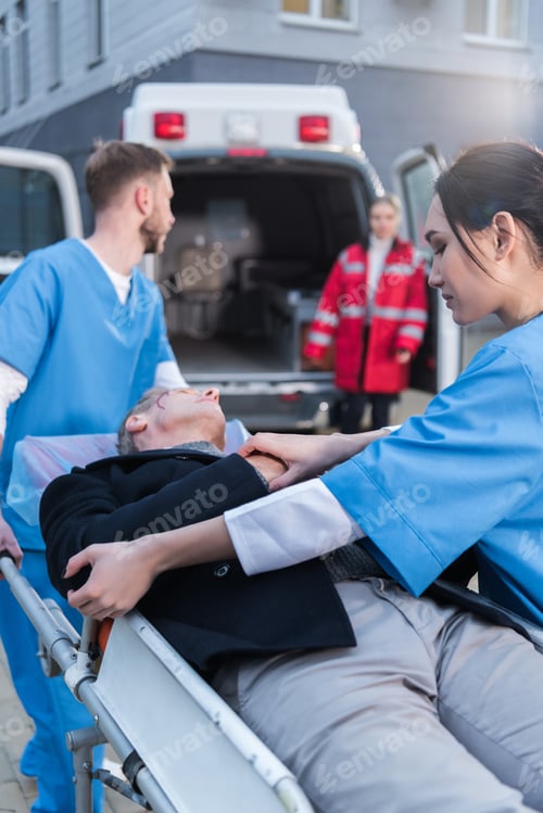 Preview: young paramedics moving wounded man on ambulance stretcher