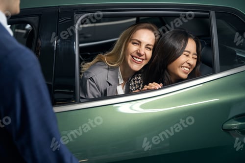 Preview: Joyful female lgbt couple on a car review before buying