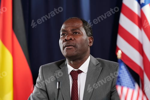 Preview: African American male delegate in elegant suit sitting in front of camera