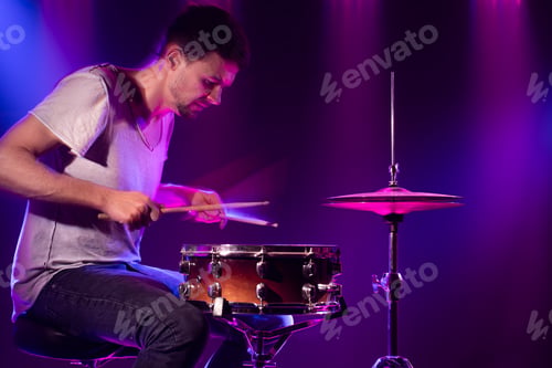 Preview: The drummer plays the drums. Beautiful blue and red background.