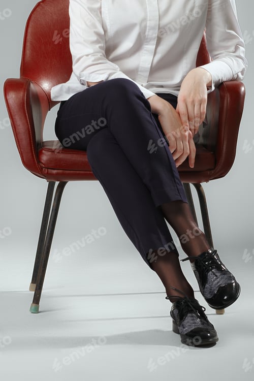 Preview: Legs in pants, hands on knees, sitting in leather armchair during an interview.