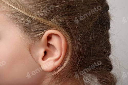 Preview: Closeup view of little girl against light gray background, focus on ear
