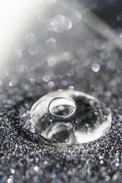 Preview: A drop of cosmetic gel on a black shining background.