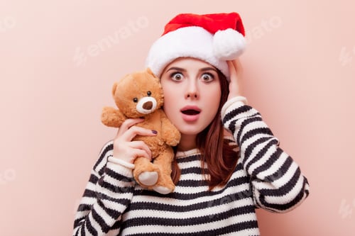 Preview: Surprised woman with teddy bear wearing Santa hat