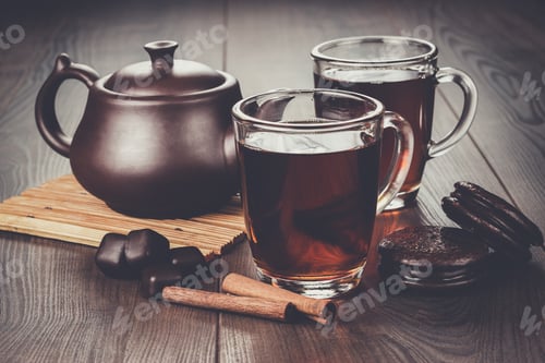 Preview: cup of tea with cinnamon sticks and teapot on the table