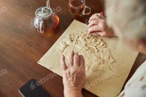 Preview: Talented senior woman making polymer clay picture at home