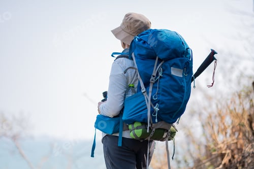 Preview: Senior woman is hiking outdoors, enjoying nature expression looks into the distance observing