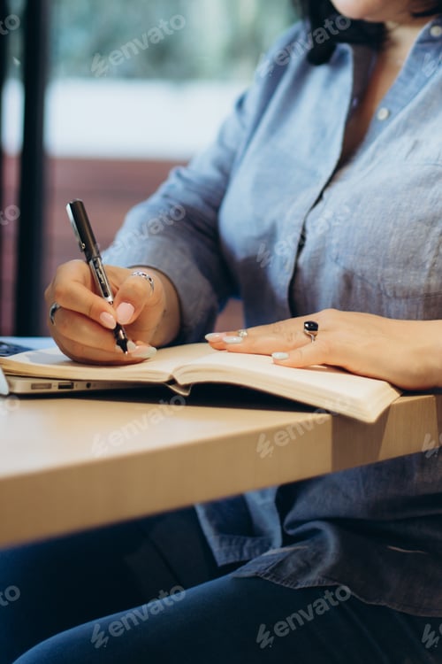 Preview: cropped photo of woman's hands making some notes in notepad. Working time