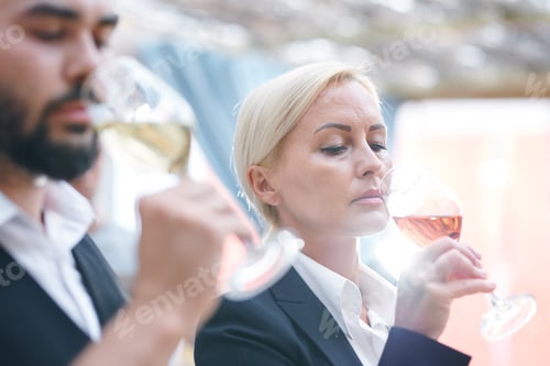 Preview: Blonde mature female sommelier smelling wine in wineglass