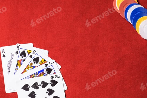 Preview: top view of red poker table with multicolored chips and unfolded playing cards