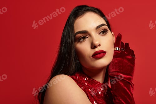Preview: A young woman with stunning red lips poses gracefully against a bold red background