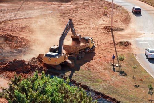Preview: A large construction vehicle in action with cars passing by
