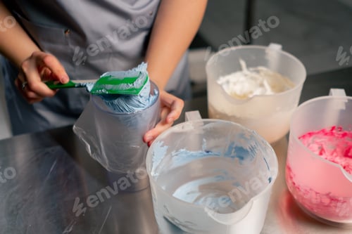 Preview: close up female baker in a professional kitchen transfers cream paste into a pastry bag