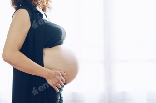Preview: Pregnant woman standing against the window