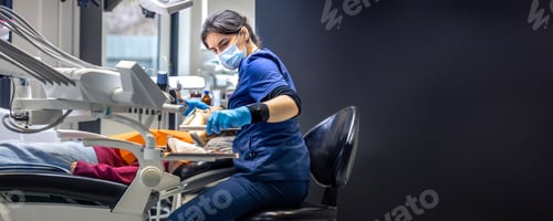 Preview: Young female dentist treating teeth of a girl in a dental office. Dentistry concept.