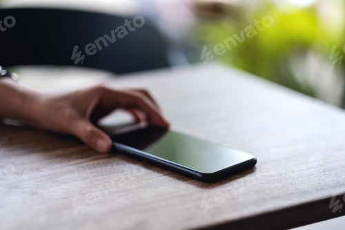 Preview: A hand grabbing and picking up mobile phone on the table