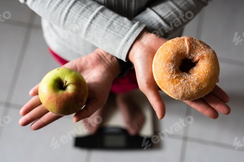 Preview: Woman Hold An Apple And Donuts And Stand On Scale At Home, Concept Of Healthy
