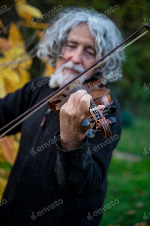 Preview: Elderly man with grey hair playing a violing outside