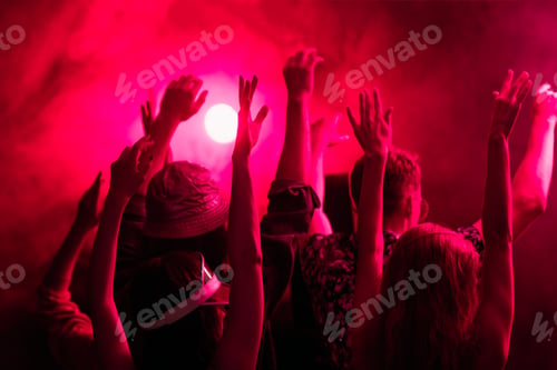 Preview: back view of people with raised hands during rave party in nightclub