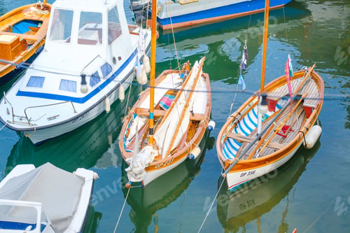 Preview: Moored boats reflected in water at port in seaside town