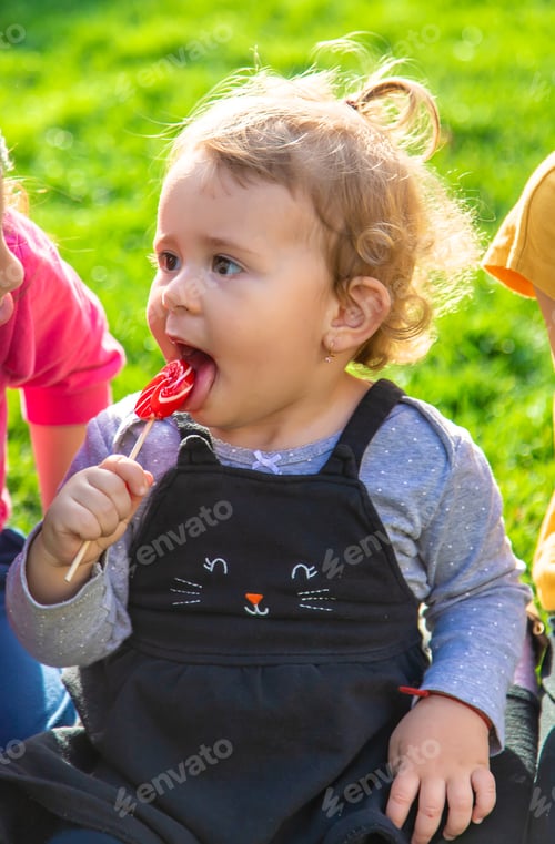 Preview: A child eats a lollipop in the park. Selective focus.