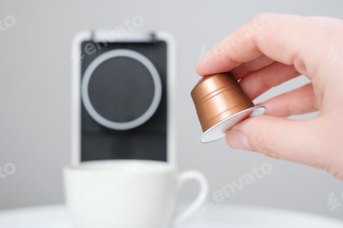 Preview: Female hand hold capsule for a coffee machine on gray background.