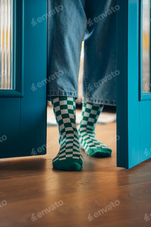Preview: Close-up of a female legs in funny plaid socks near open blue doors