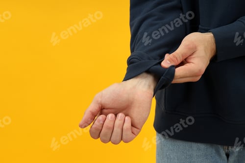 Preview: Man check the quality of hoodie on yellow background, space for text