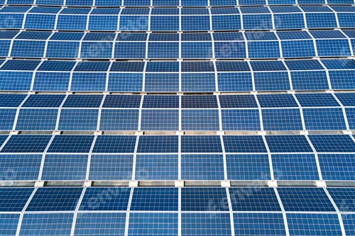 Preview: Aerial view of solar power plant with blue photovoltaic panels mounted on industrial building roof