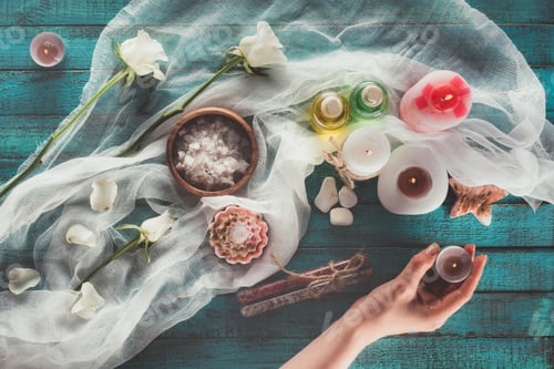 Preview: Top view of Woman making spa treatment decoration, holding candle