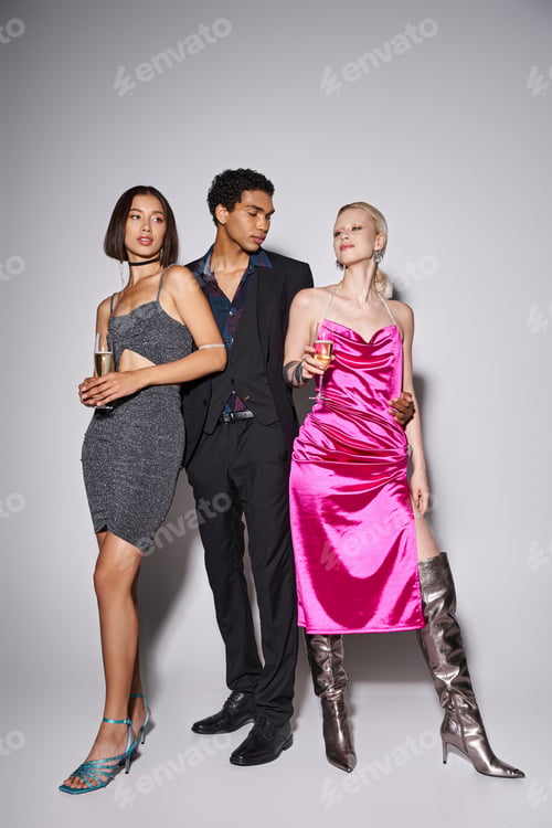 Preview: african american man posing with two multiethnic women in dresses with champagne on New Year party