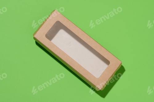 Preview: Rectangular cardboard box with a transparent plastic lid on a green background, top view