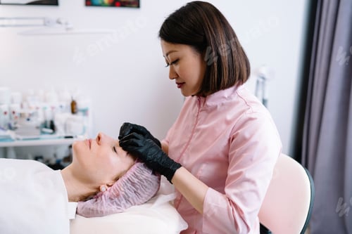 Preview: Professional beautician massaging face of client in salon
