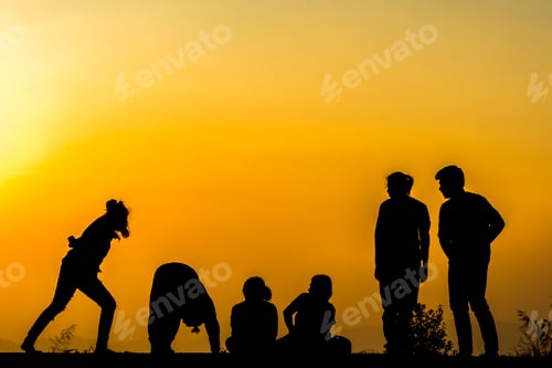 Preview: silhouette of people group practicing yoga on the beach at sunset
