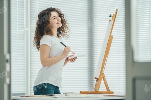 Preview: The happy woman painting a picture on the easel.